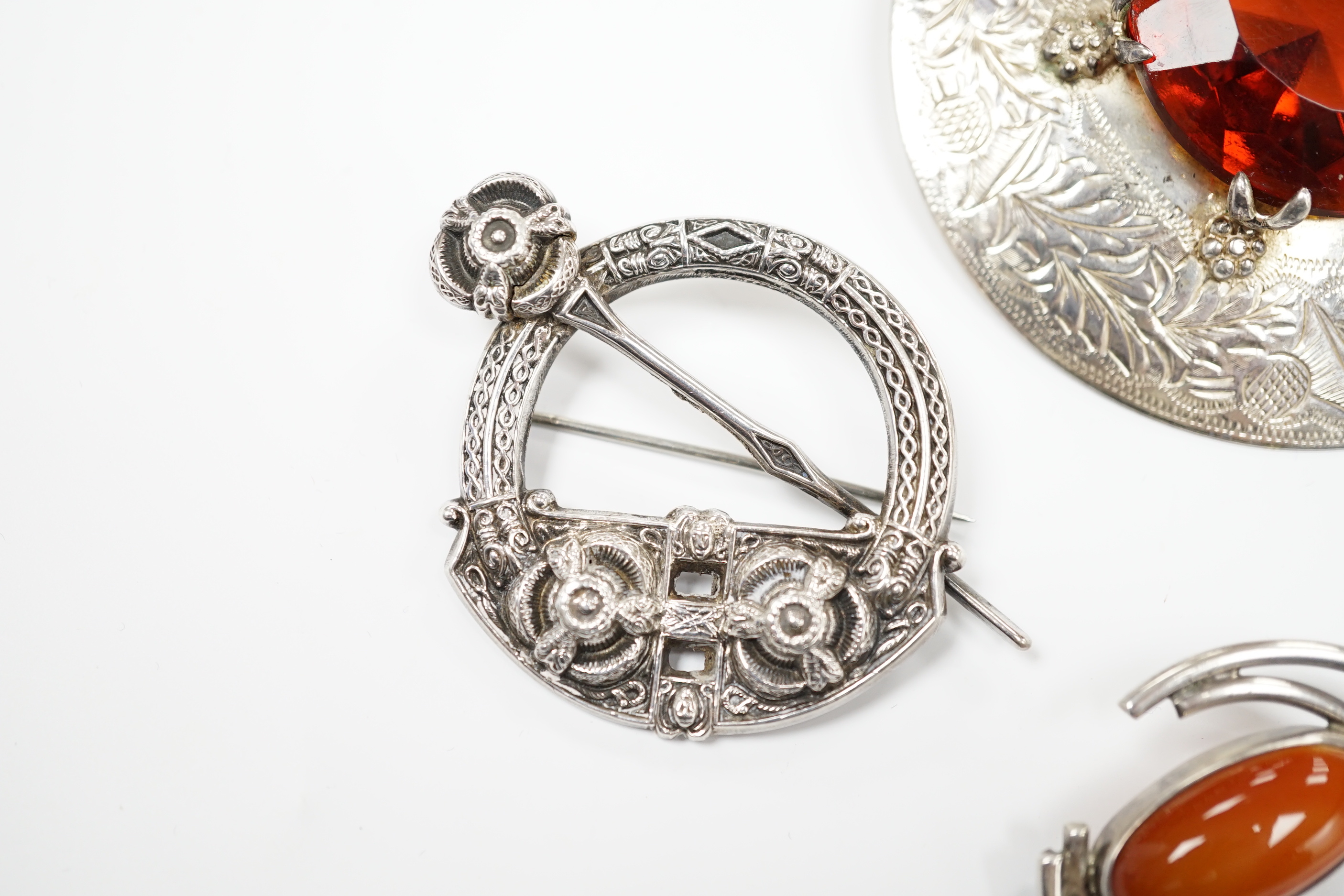 A 1950's Scottish silver and citrine coloured paste set circular brooch, 68mm, an Edwardian silver Celtic style brooch and three other white metal brooches, including Scottish hardstone set.
